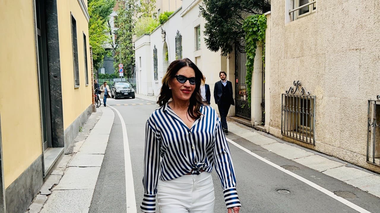 Giselle Koy on the streets of Milan during Design Week — striped silk, white trousers, the energy of the city