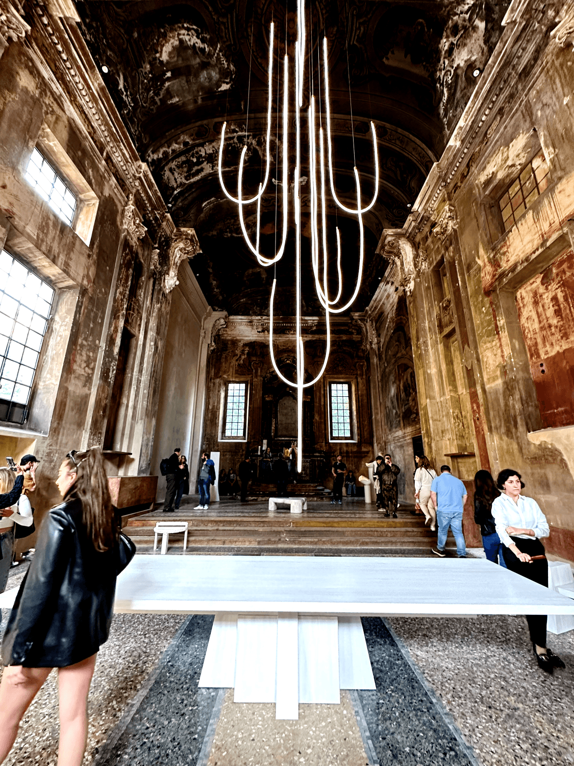 Design Week installation — a sculptural light fixture descending through a frescoed palazzo ceiling, the ancient and the new in conversation