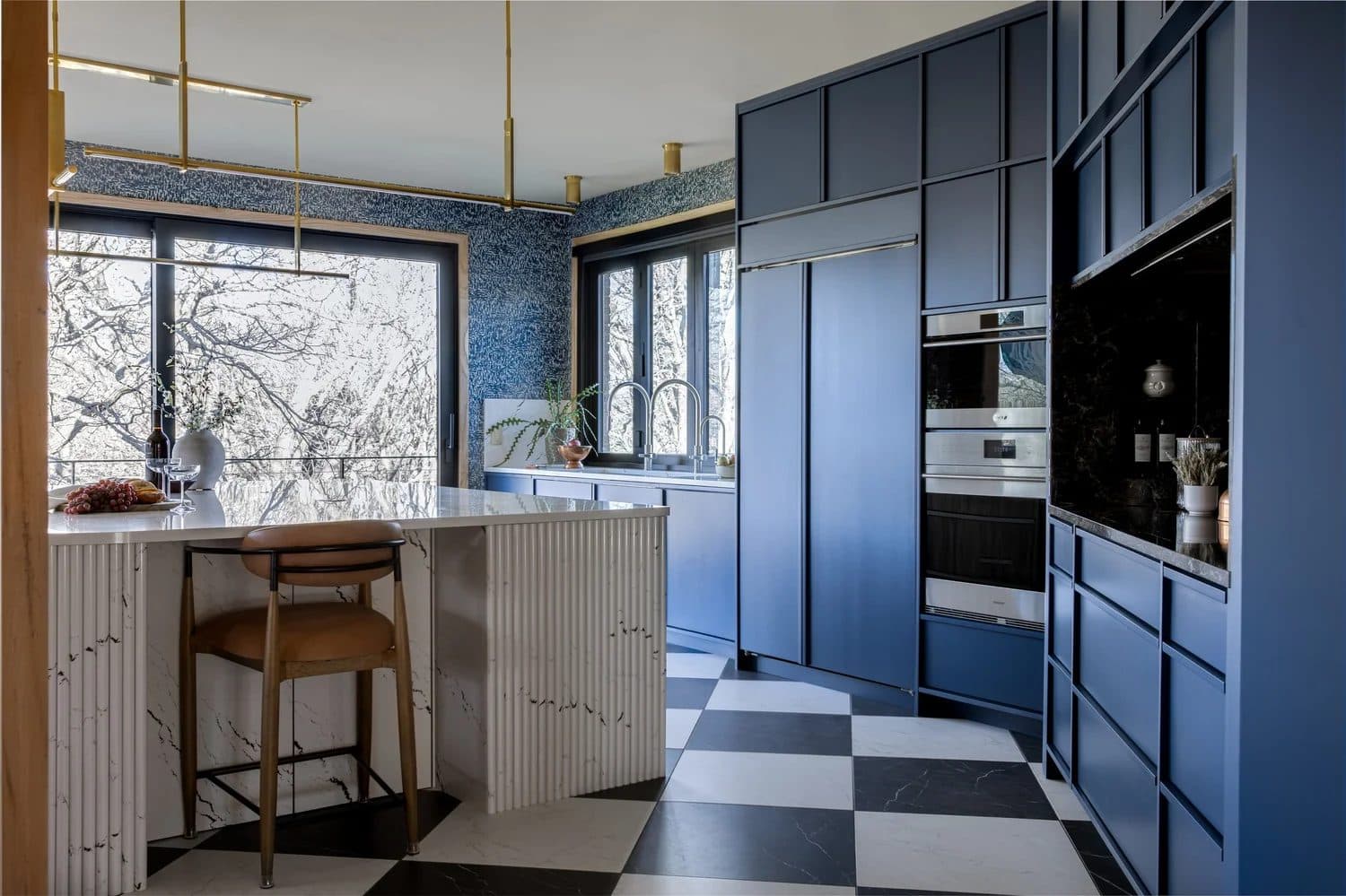Deep navy blue floor-to-ceiling kitchen with black and white checkered floor and white fluted marble island.