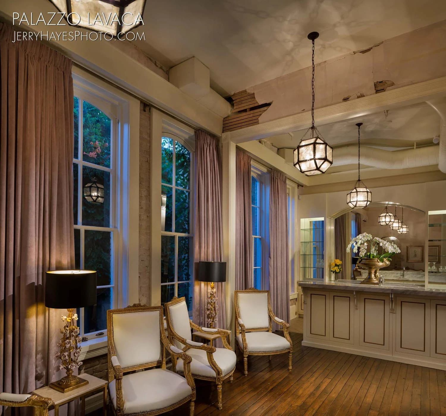 Blush silk curtains and antique chairs in a considered lounge setting